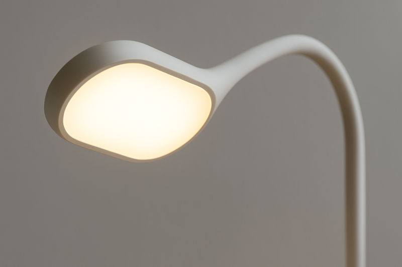 A close-up on an eye-caring LED lamp head, showing its soft, even light, with the flexible arm in the background