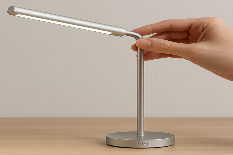 alt text: A close-up on the elegant, minimalist design of a Roye Lamp, showing its small base, clean lines, and a hand easily adjusting the flexible lamp head.