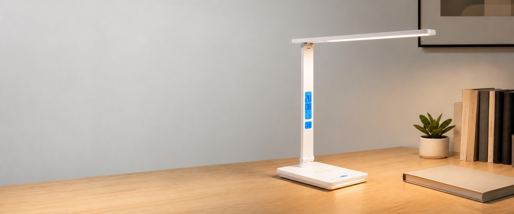 Illuminated white RoyeLamp desk lamp with a digital display and wireless charging base in a styled workspace
